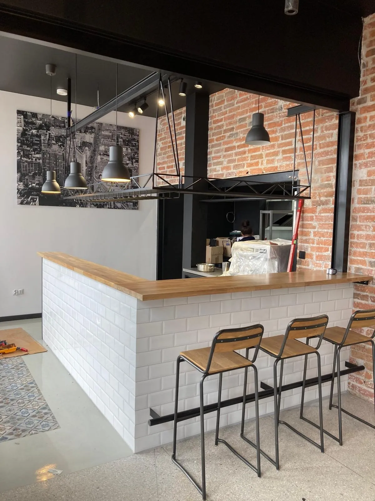 Bar w lokalu z ceglaną ścianą, stalowa konstrukcja baru i półka nad nim z lampami